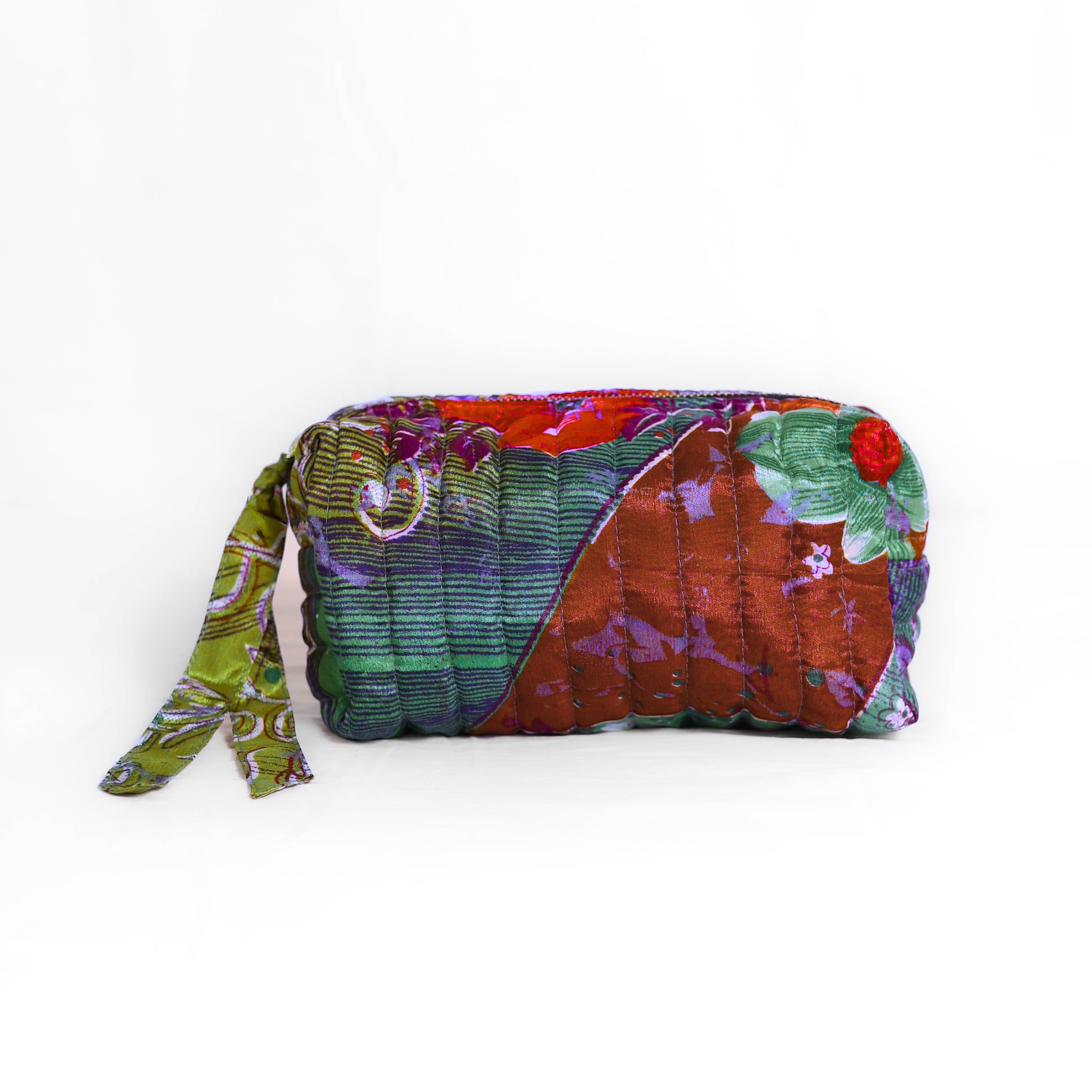 Quilted dumpling bag made from repurposed vintage sari fabric with stitched detailing and a structured rectangular shape. The bag features a zip closure and a fabric tie