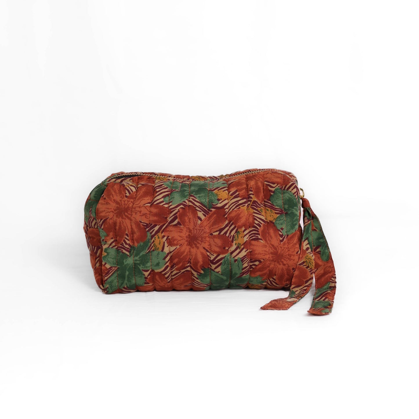 Quilted dumpling bag made from repurposed vintage sari fabric with stitched detailing and a structured rectangular shape. The bag features a zip closure and a fabric tie