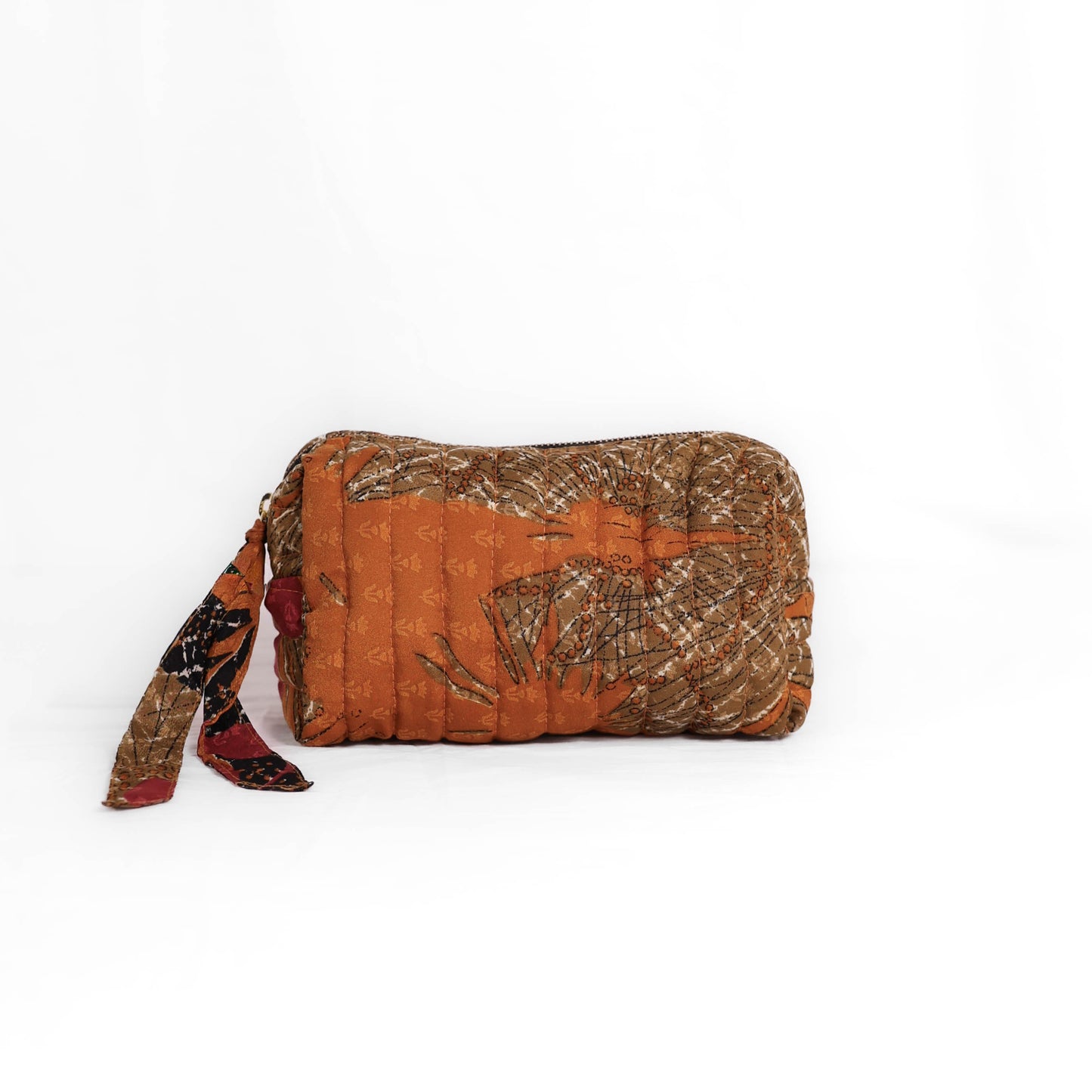 Quilted dumpling bag made from repurposed vintage sari fabric with stitched detailing and a structured rectangular shape. The bag features a zip closure and a fabric tie