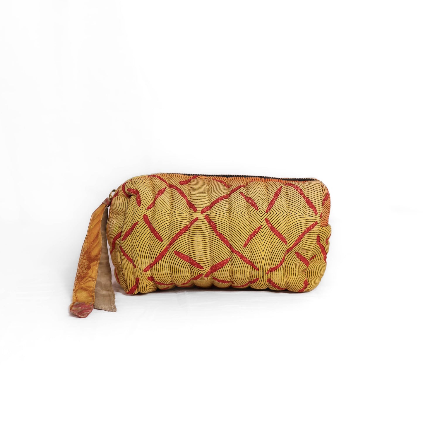 Quilted dumpling bag made from repurposed vintage sari fabric with stitched detailing and a structured rectangular shape. The bag features a zip closure and a fabric tie