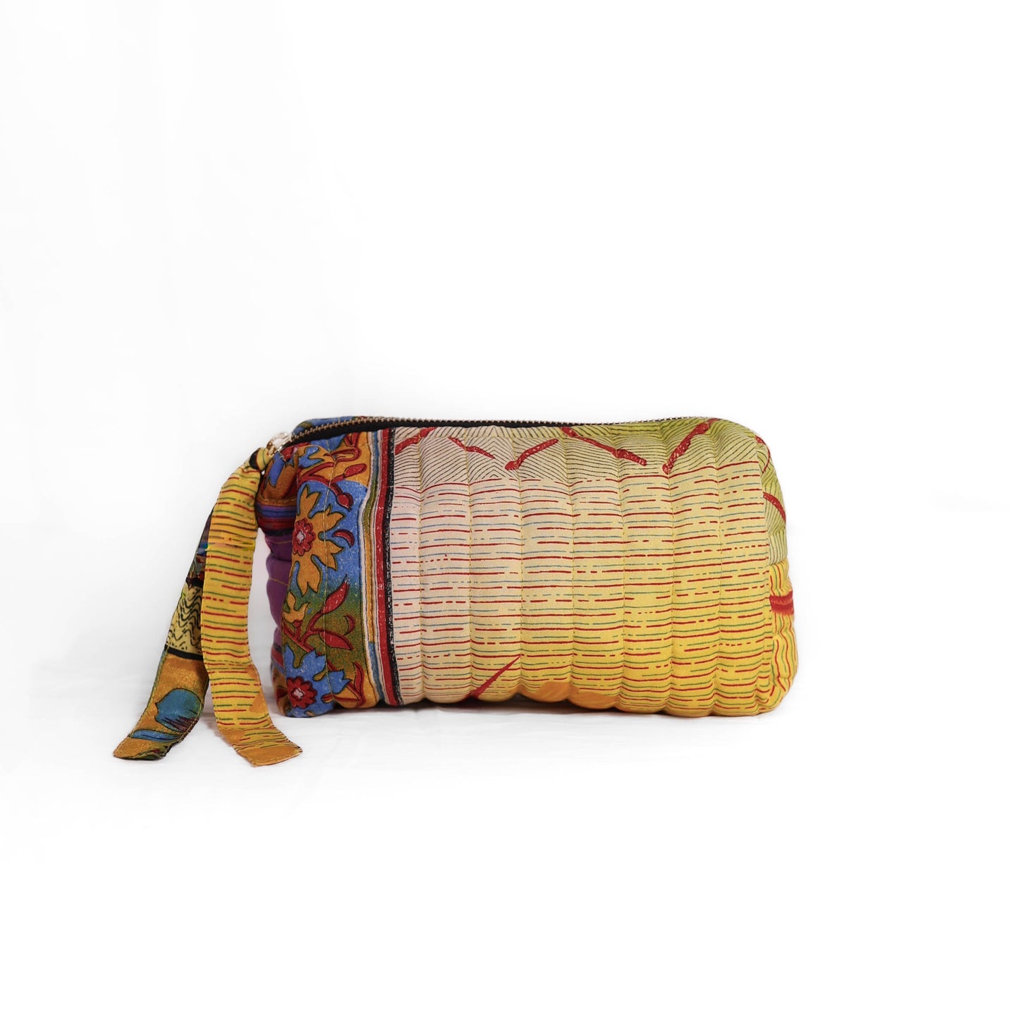 Quilted dumpling bag made from repurposed vintage sari fabric with stitched detailing and a structured rectangular shape. The bag features a zip closure and a fabric tie