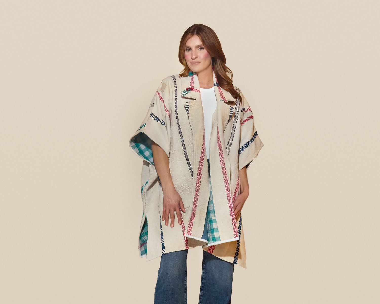 Mid-length open-front jacket with wide sleeves, made from a cream woven textile with vertical multicolor stripe patterns and a contrasting green check lining visible at the edges.
