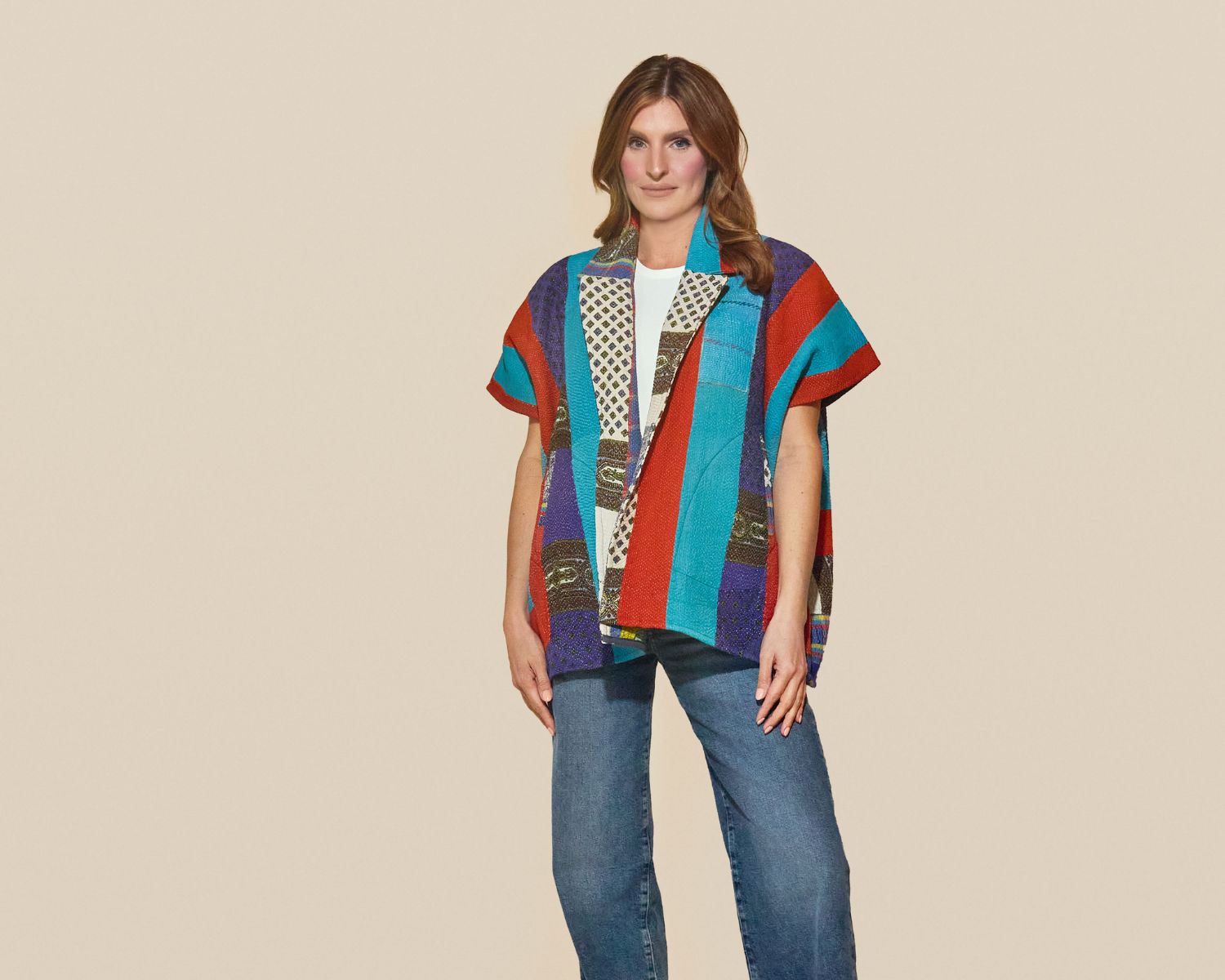 Mid-length open-front jacket with wide sleeves, made from multicolored woven textiles with bold vertical stripes in teal, red, and purple and mixed patterned panels.