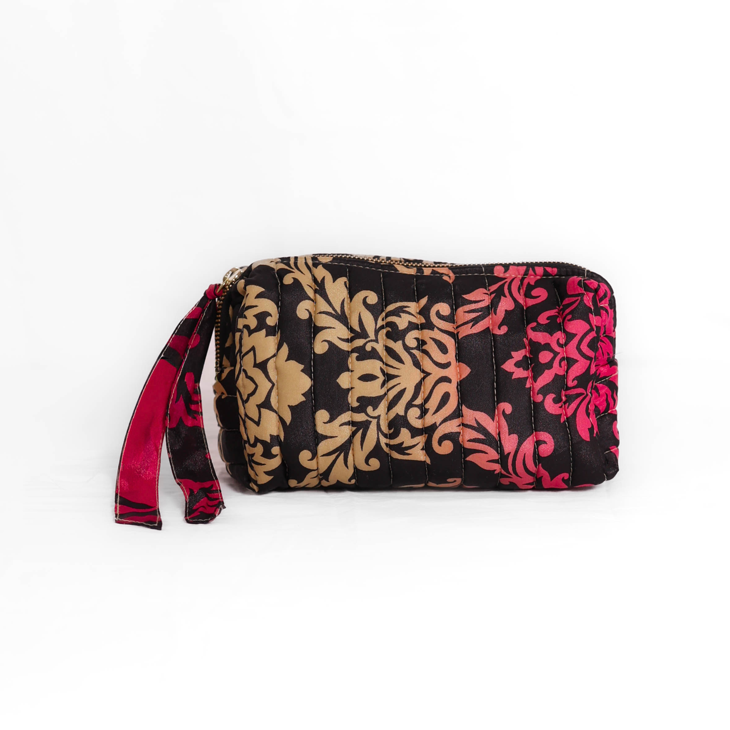 Quilted dumpling bag made from repurposed vintage sari fabric with stitched detailing and a structured rectangular shape. The bag features a zip closure and a fabric tie