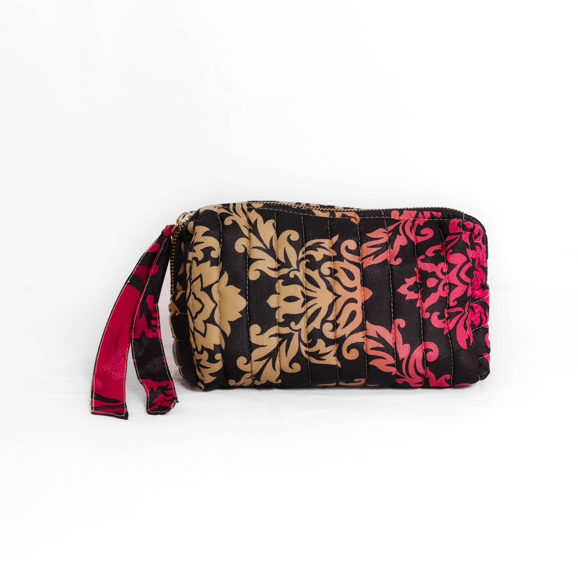 Quilted dumpling bag made from repurposed vintage sari fabric with stitched detailing and a structured rectangular shape. The bag features a zip closure and a fabric tie