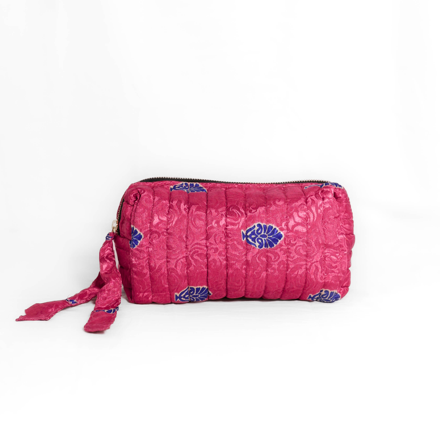 Quilted dumpling bag made from repurposed vintage sari fabric with stitched detailing and a structured rectangular shape. The bag features a zip closure and a fabric tie
