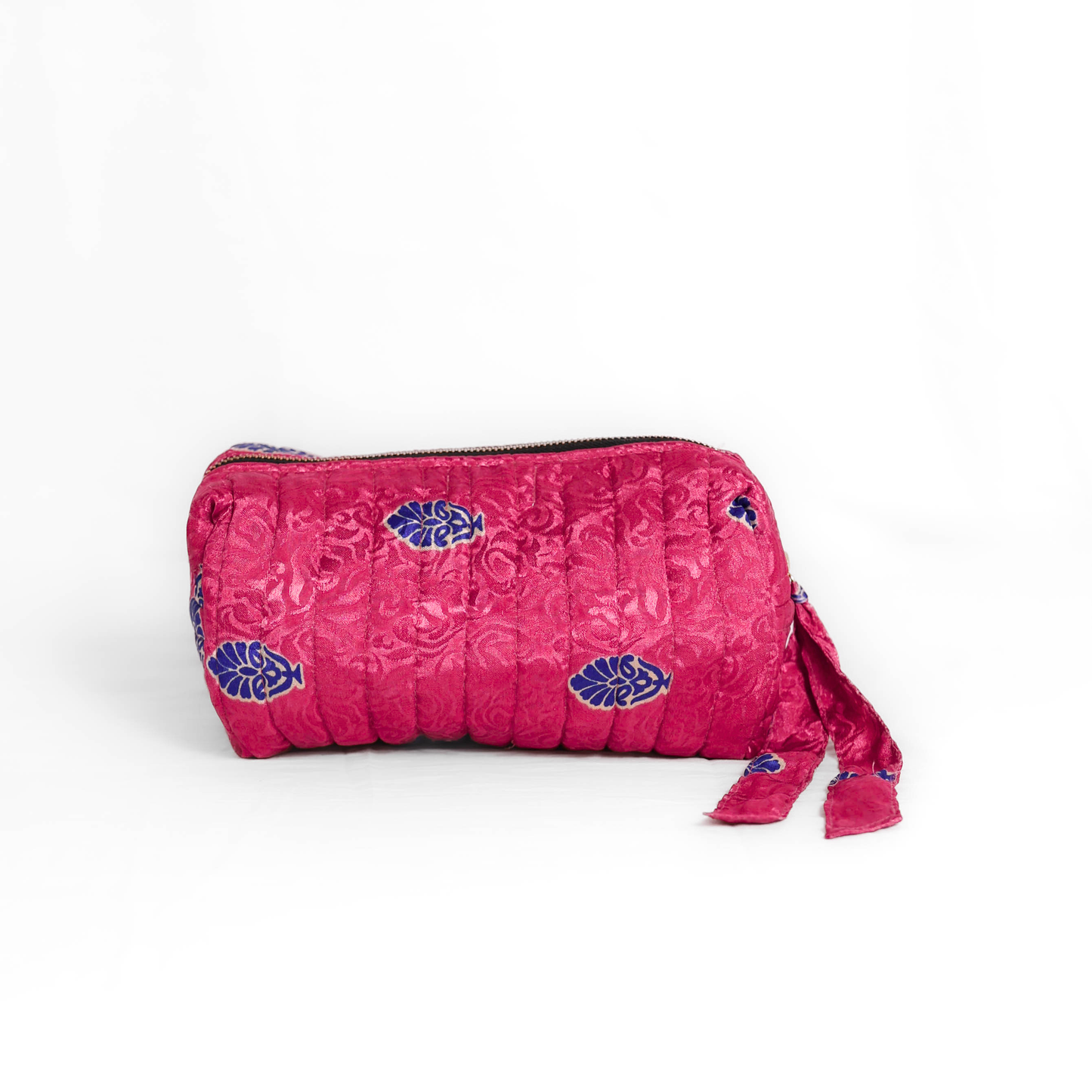 Quilted dumpling bag made from repurposed vintage sari fabric with stitched detailing and a structured rectangular shape. The bag features a zip closure and a fabric tie
