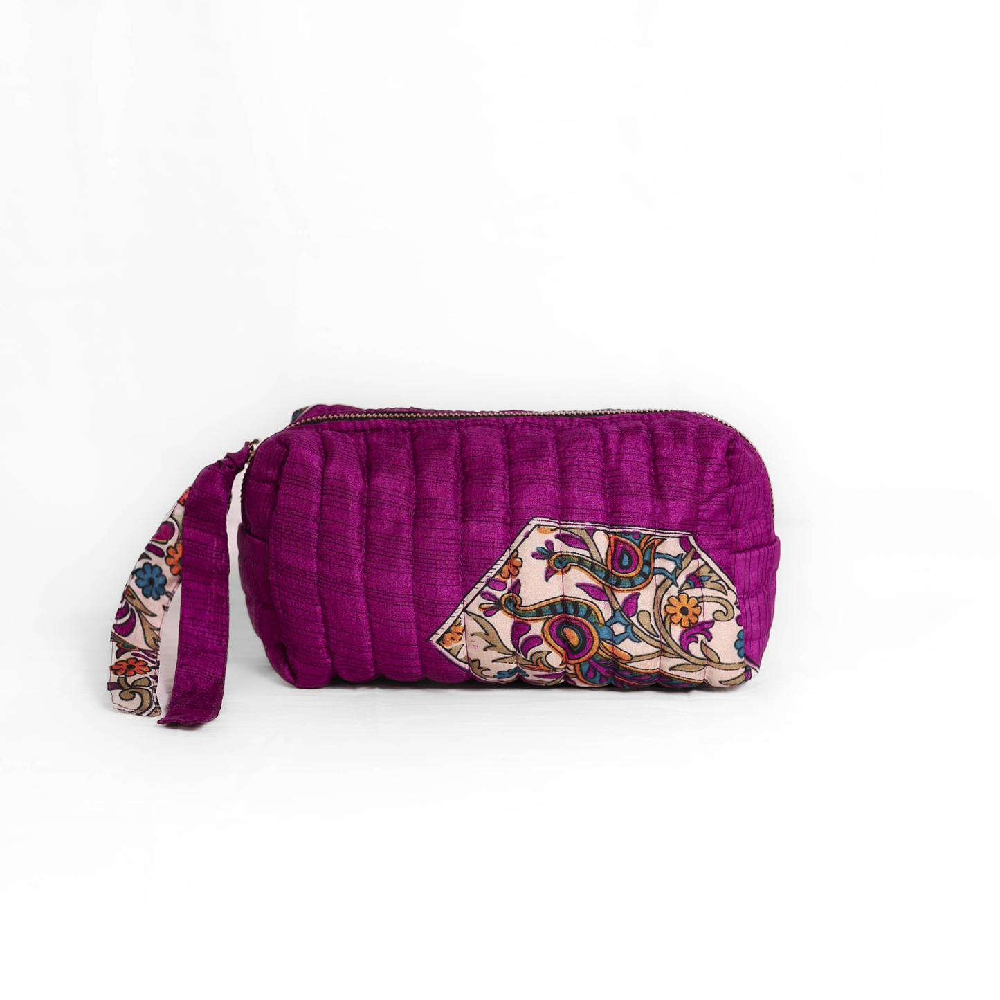 Quilted dumpling bag made from repurposed vintage sari fabric with stitched detailing and a structured rectangular shape. The bag features a zip closure and a fabric tie
