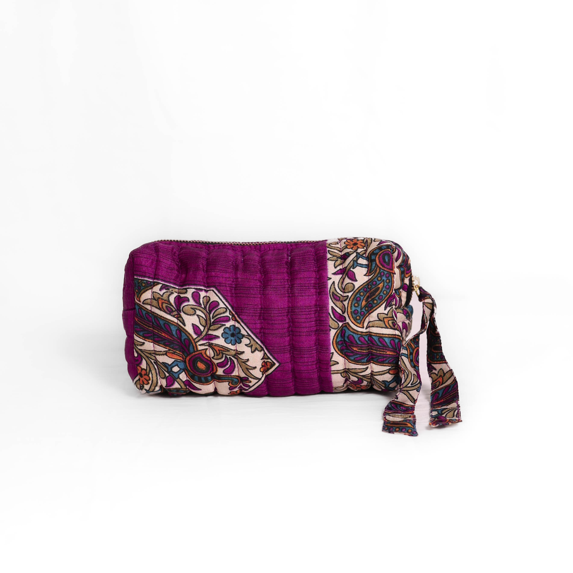 Quilted dumpling bag made from repurposed vintage sari fabric with stitched detailing and a structured rectangular shape. The bag features a zip closure and a fabric tie
