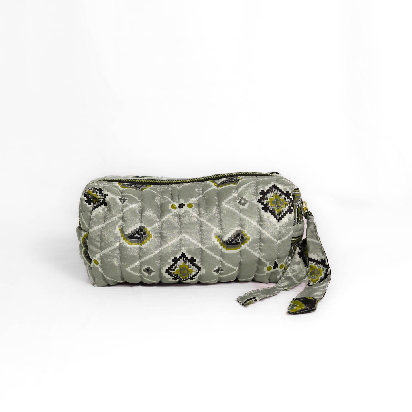 Quilted dumpling bag made from repurposed vintage sari fabric with stitched detailing and a structured rectangular shape. The bag features a zip closure and a fabric tie

