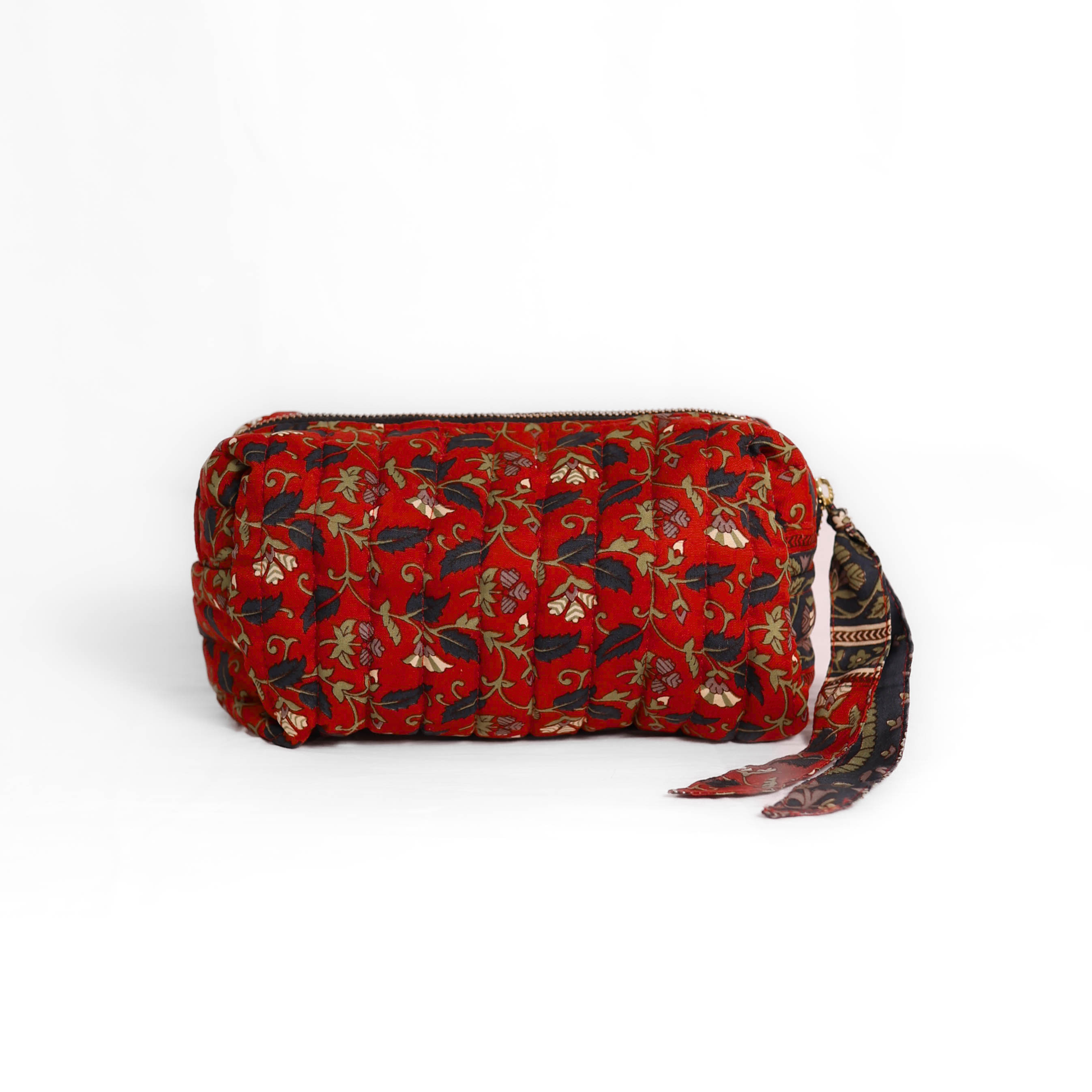 Quilted dumpling bag made from repurposed vintage sari fabric with stitched detailing and a structured rectangular shape. The bag features a zip closure and a fabric tie

