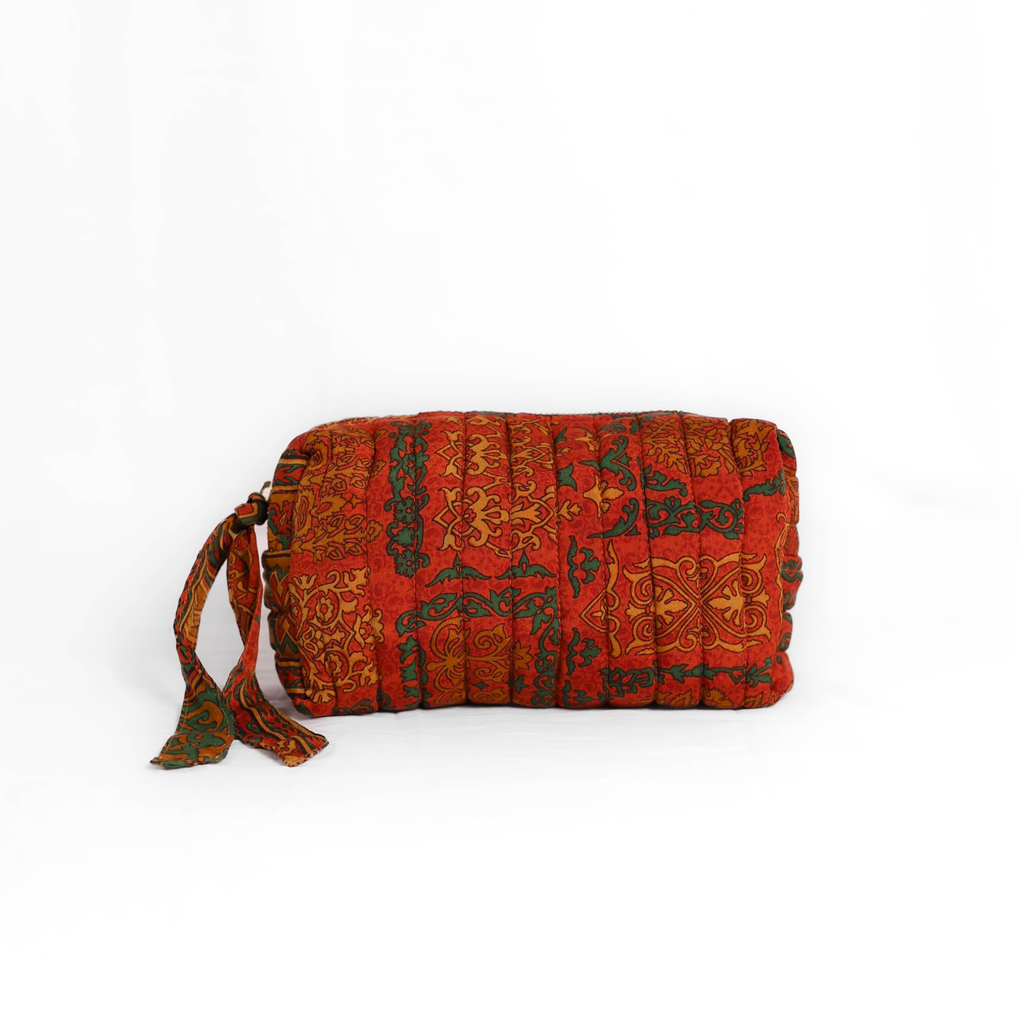 Quilted dumpling bag made from repurposed vintage sari fabric with stitched detailing and a structured rectangular shape. The bag features a zip closure and a fabric tie
