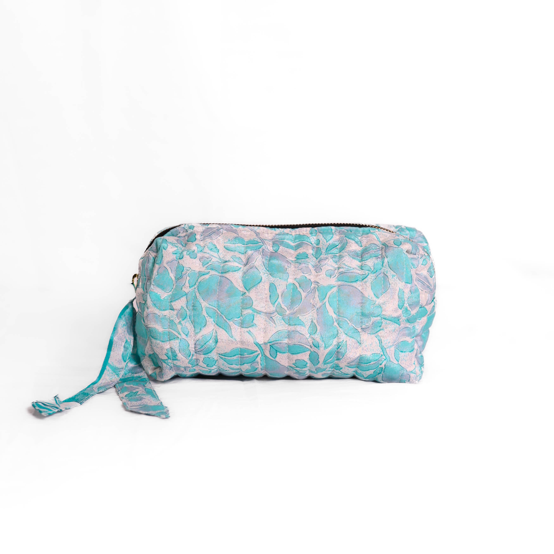 Quilted dumpling bag made from repurposed vintage sari fabric with stitched detailing and a structured rectangular shape. The bag features a zip closure and a fabric tie
