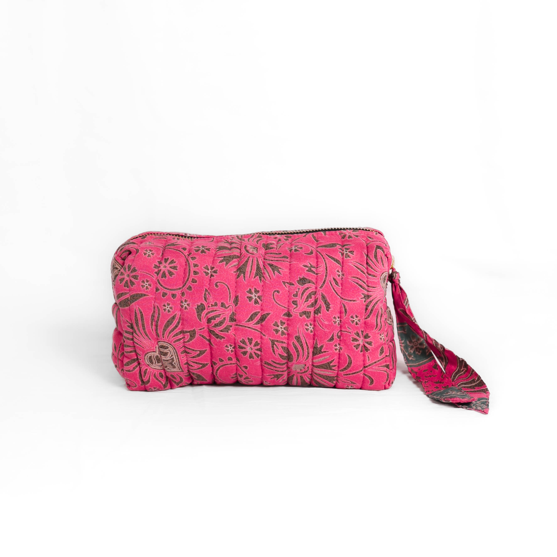 Quilted dumpling bag made from repurposed vintage sari fabric with stitched detailing and a structured rectangular shape. The bag features a zip closure and a fabric tie
