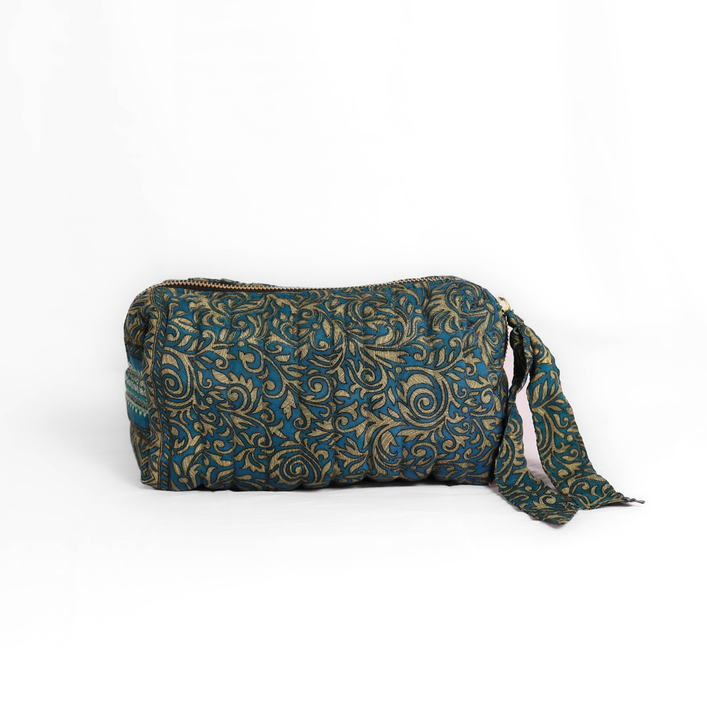 Quilted dumpling bag made from repurposed vintage sari fabric with stitched detailing and a structured rectangular shape. The bag features a zip closure and a fabric tie
