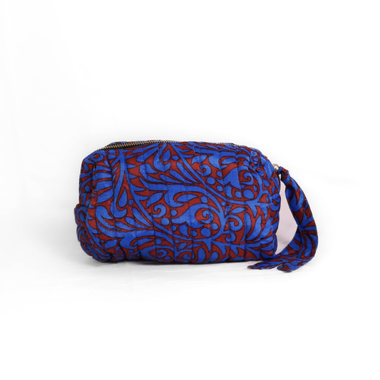 Quilted dumpling bag made from repurposed vintage sari fabric with stitched detailing and a structured rectangular shape. The bag features a zip closure and a fabric tie