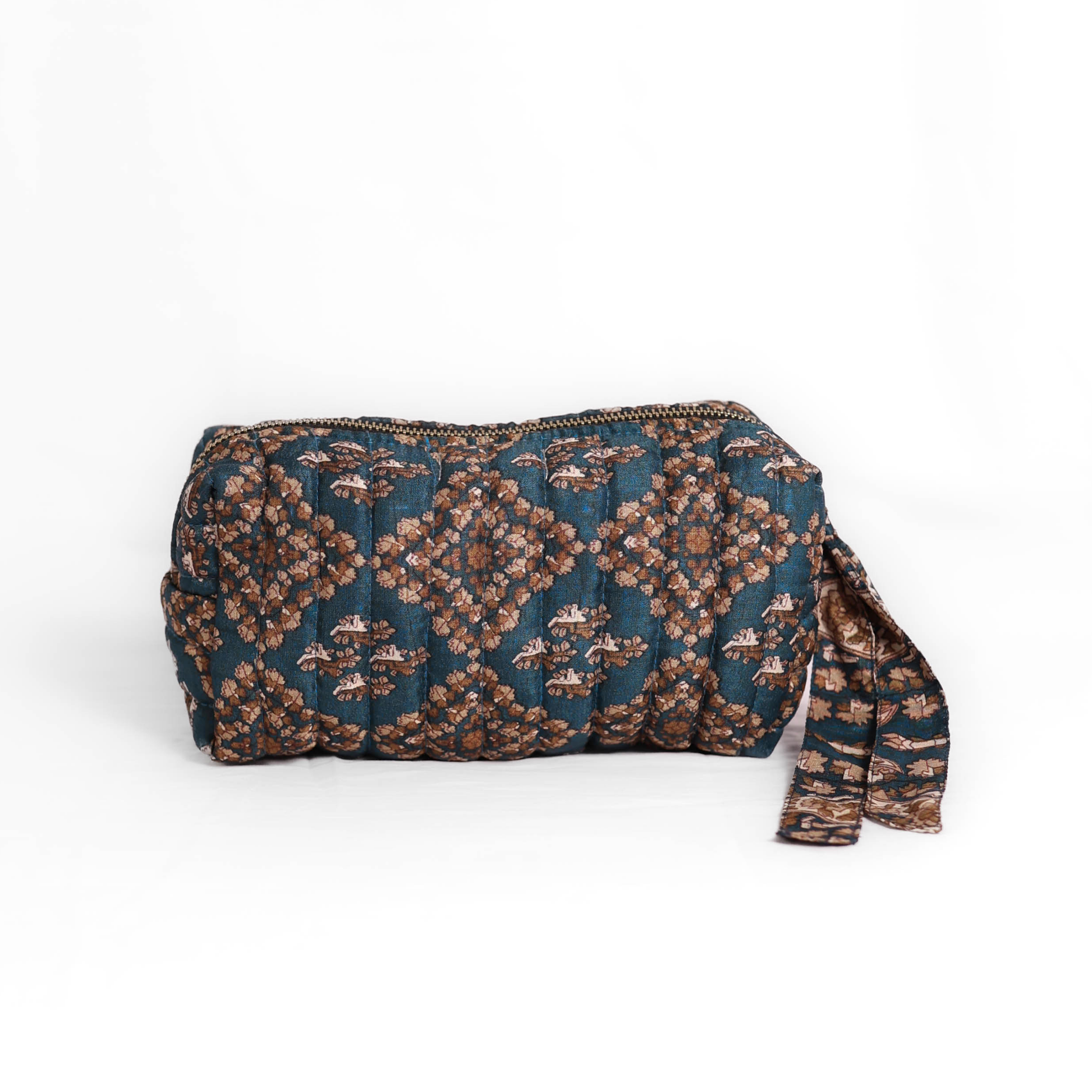 Quilted dumpling bag made from repurposed vintage sari fabric with stitched detailing and a structured rectangular shape. The bag features a zip closure and a fabric tie