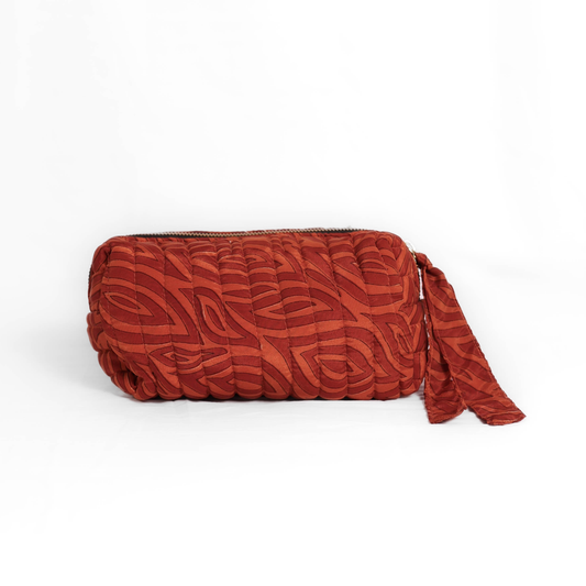 Quilted dumpling bag made from repurposed vintage sari fabric with stitched detailing and a structured rectangular shape. The bag features a zip closure and a fabric tie