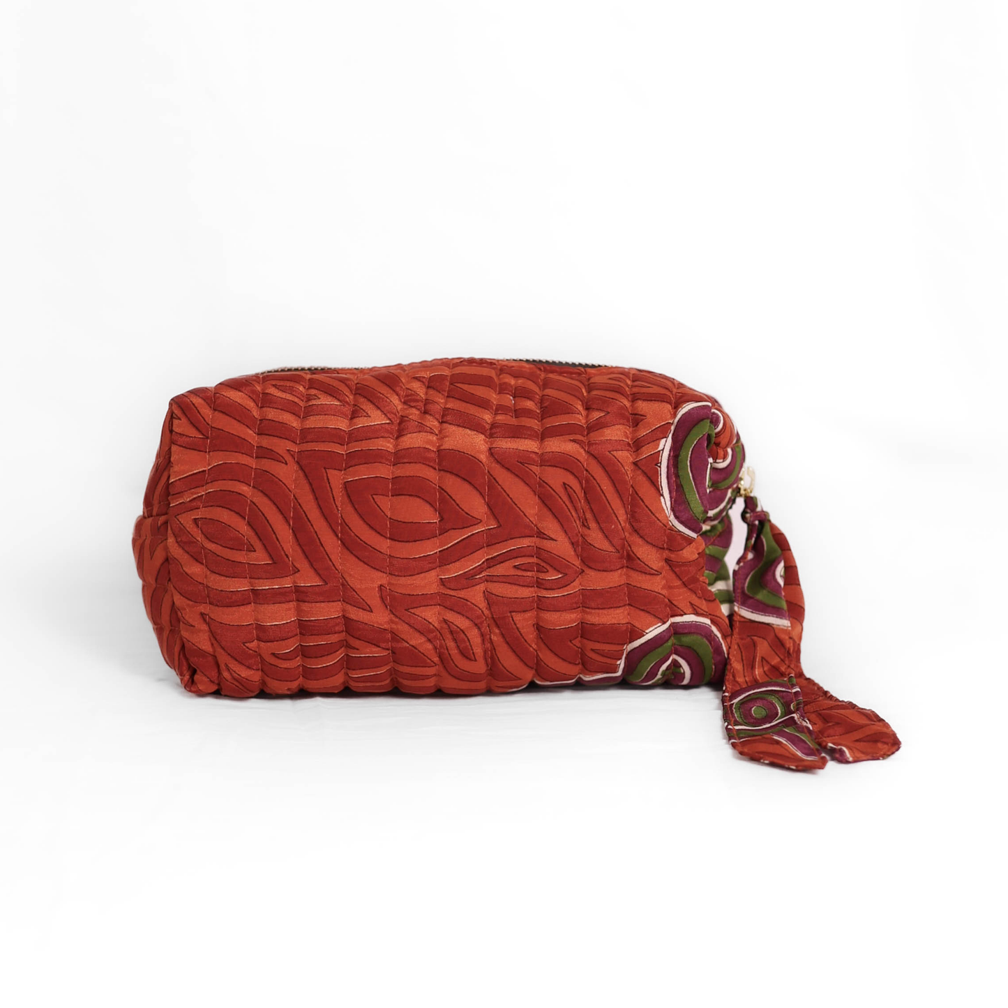 Quilted dumpling bag made from repurposed vintage sari fabric with stitched detailing and a structured rectangular shape. The bag features a zip closure and a fabric tie