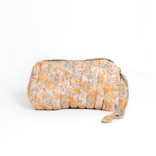 Quilted dumpling bag made from repurposed vintage sari fabric with stitched detailing and a structured rectangular shape. The bag features a zip closure and a fabric tie
