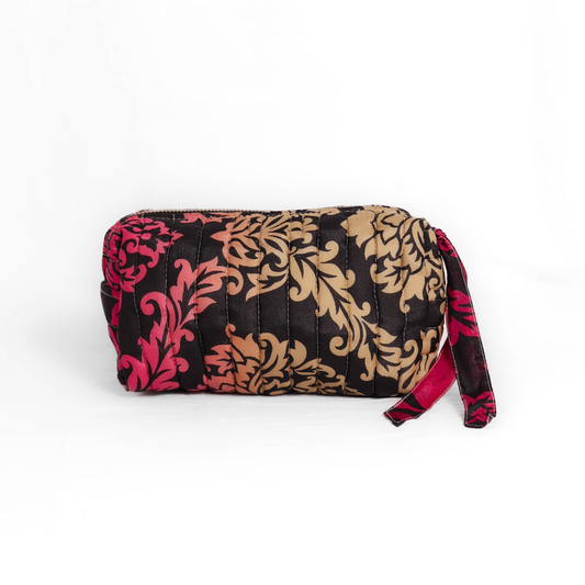 Quilted dumpling bag made from repurposed vintage sari fabric with stitched detailing and a structured rectangular shape. The bag features a zip closure and a fabric tie