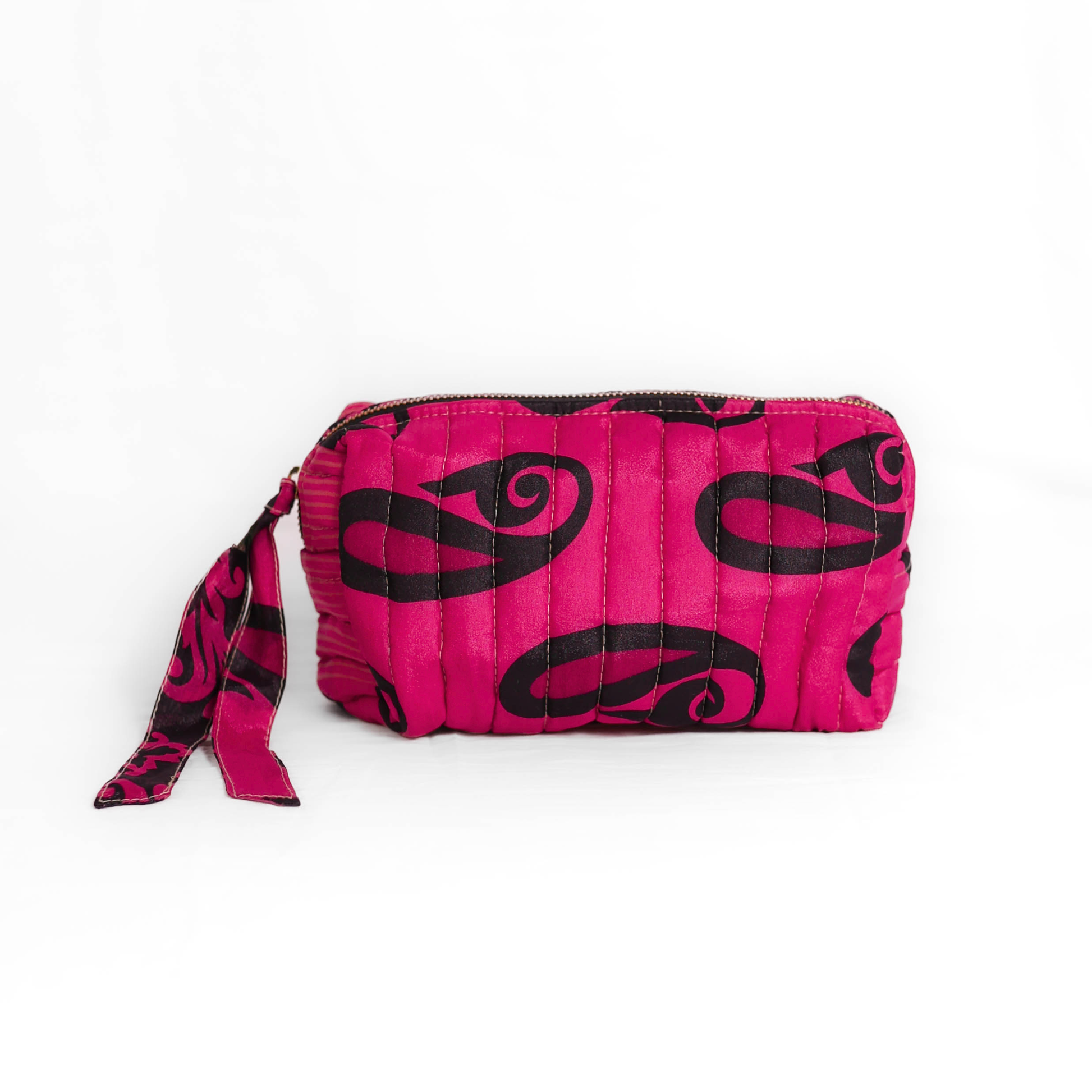 Quilted dumpling bag made from repurposed vintage sari fabric with stitched detailing and a structured rectangular shape. The bag features a zip closure and a fabric tie
