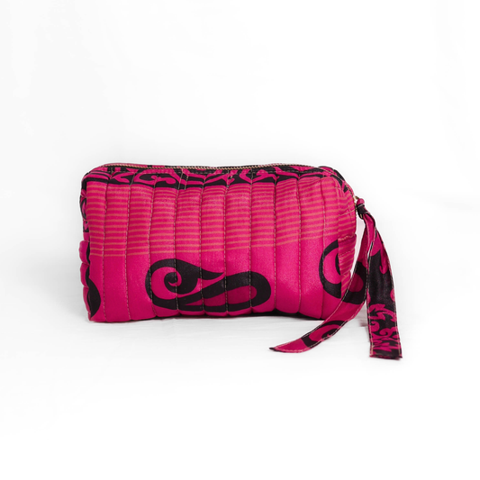 Quilted dumpling bag made from repurposed vintage sari fabric with stitched detailing and a structured rectangular shape. The bag features a zip closure and a fabric tie