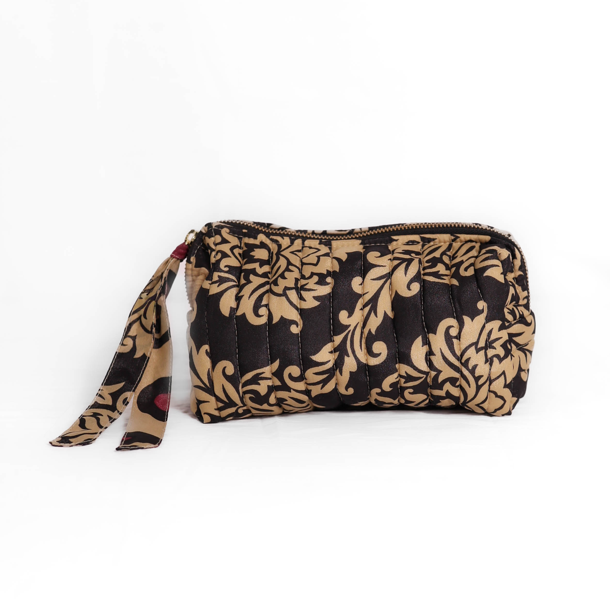 Quilted dumpling bag made from repurposed vintage sari fabric with stitched detailing and a structured rectangular shape. The bag features a zip closure and a fabric tie