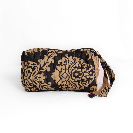 Quilted dumpling bag made from repurposed vintage sari fabric with stitched detailing and a structured rectangular shape. The bag features a zip closure and a fabric tie
