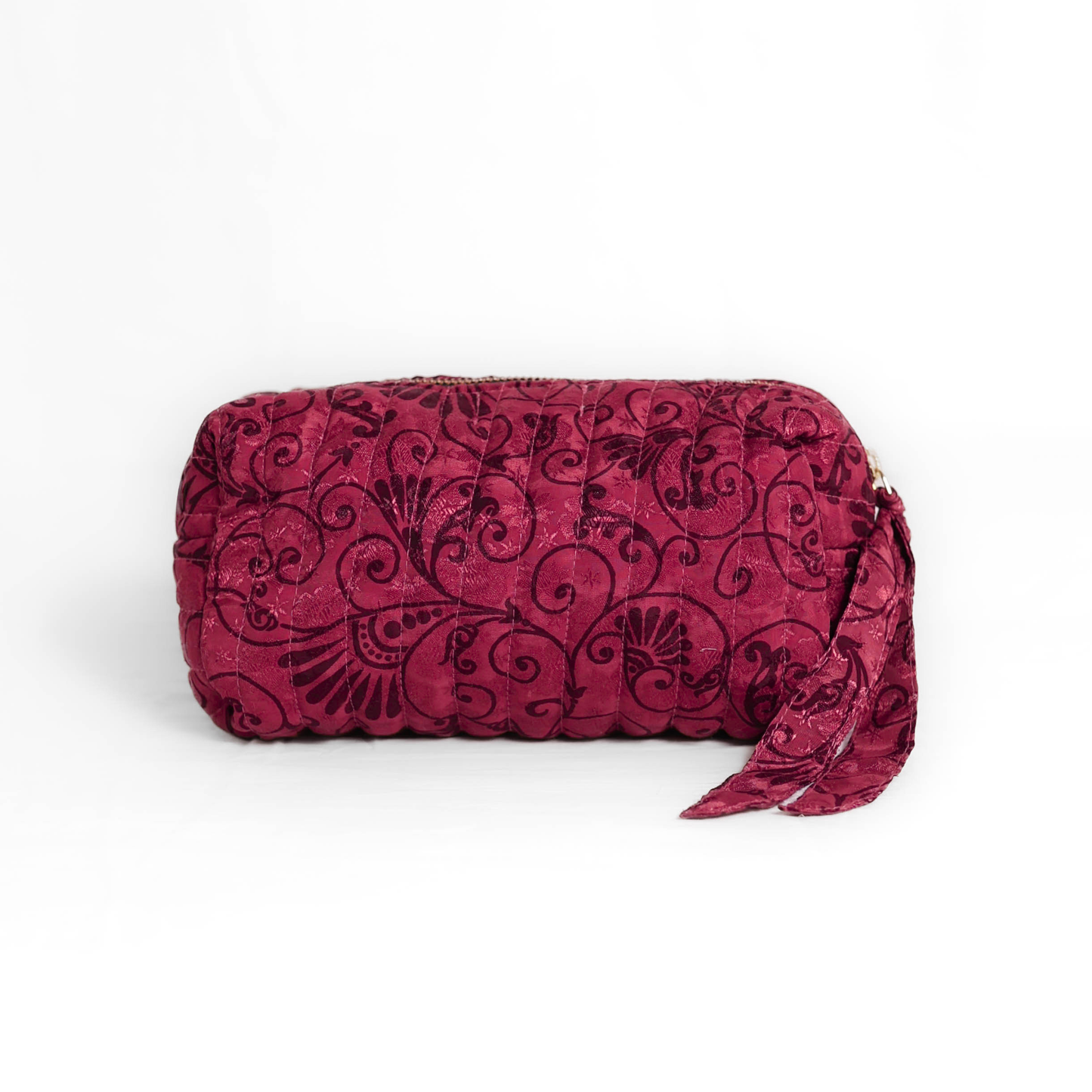 Quilted dumpling bag made from repurposed vintage sari fabric with stitched detailing and a structured rectangular shape. The bag features a zip closure and a fabric tie