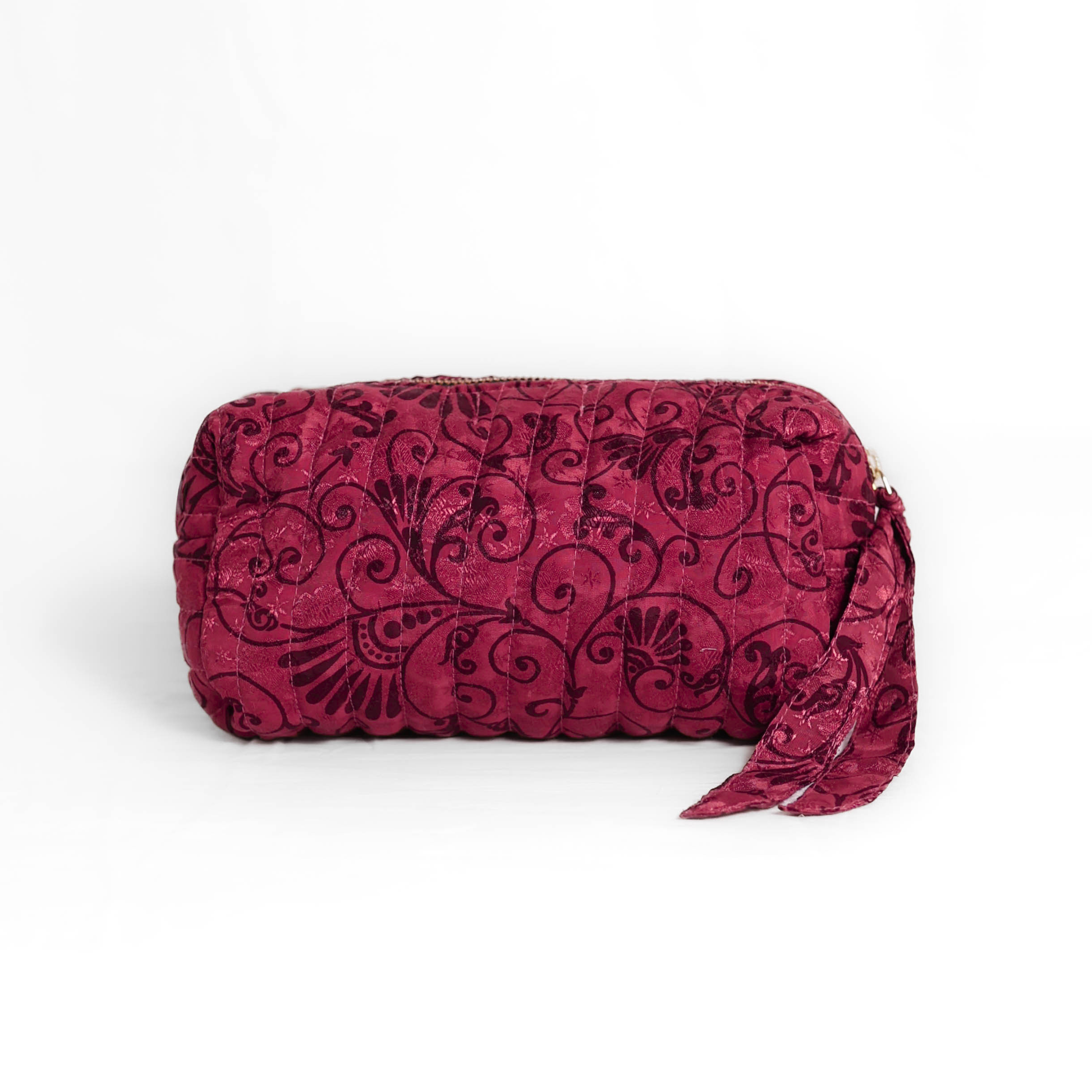 Quilted dumpling bag made from repurposed vintage sari fabric with stitched detailing and a structured rectangular shape. The bag features a zip closure and a fabric tie