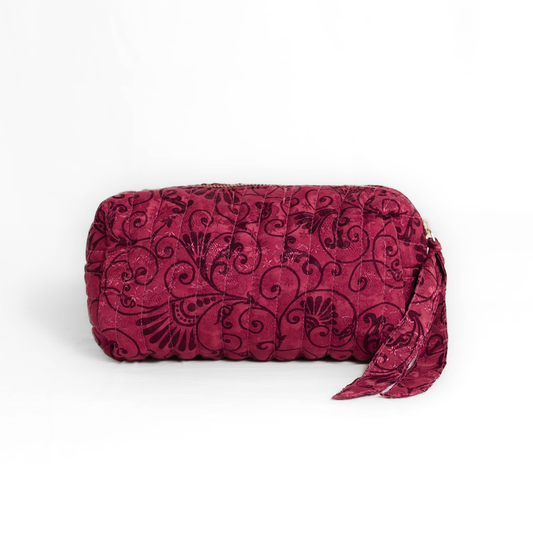 Quilted dumpling bag made from repurposed vintage sari fabric with stitched detailing and a structured rectangular shape. The bag features a zip closure and a fabric tie