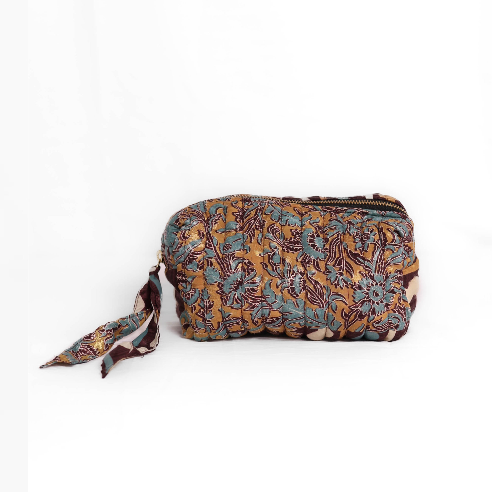 Quilted dumpling bag made from repurposed vintage sari fabric with stitched detailing and a structured rectangular shape. The bag features a zip closure and a fabric tie