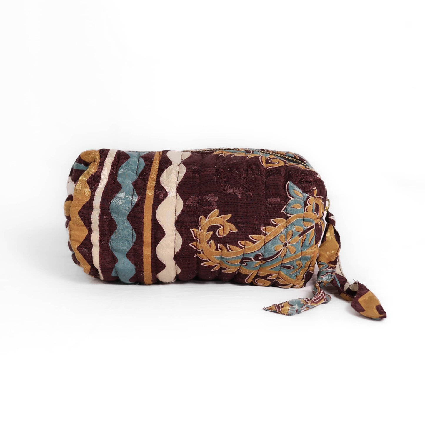 Quilted dumpling bag made from repurposed vintage sari fabric with stitched detailing and a structured rectangular shape. The bag features a zip closure and a fabric tie