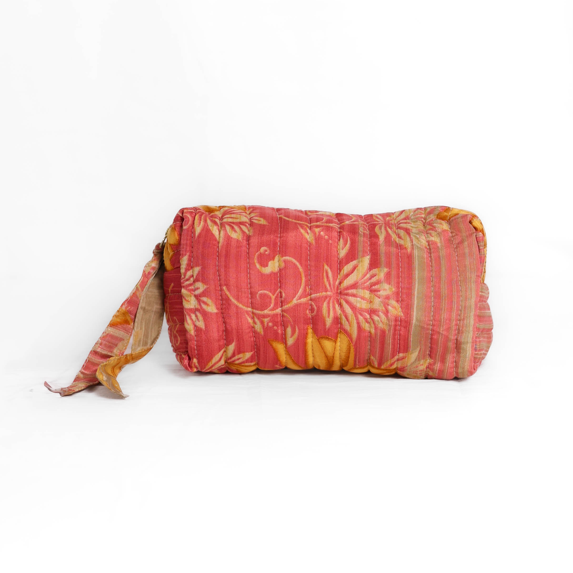 Quilted dumpling bag made from repurposed vintage sari fabric with stitched detailing and a structured rectangular shape. The bag features a zip closure and a fabric tie