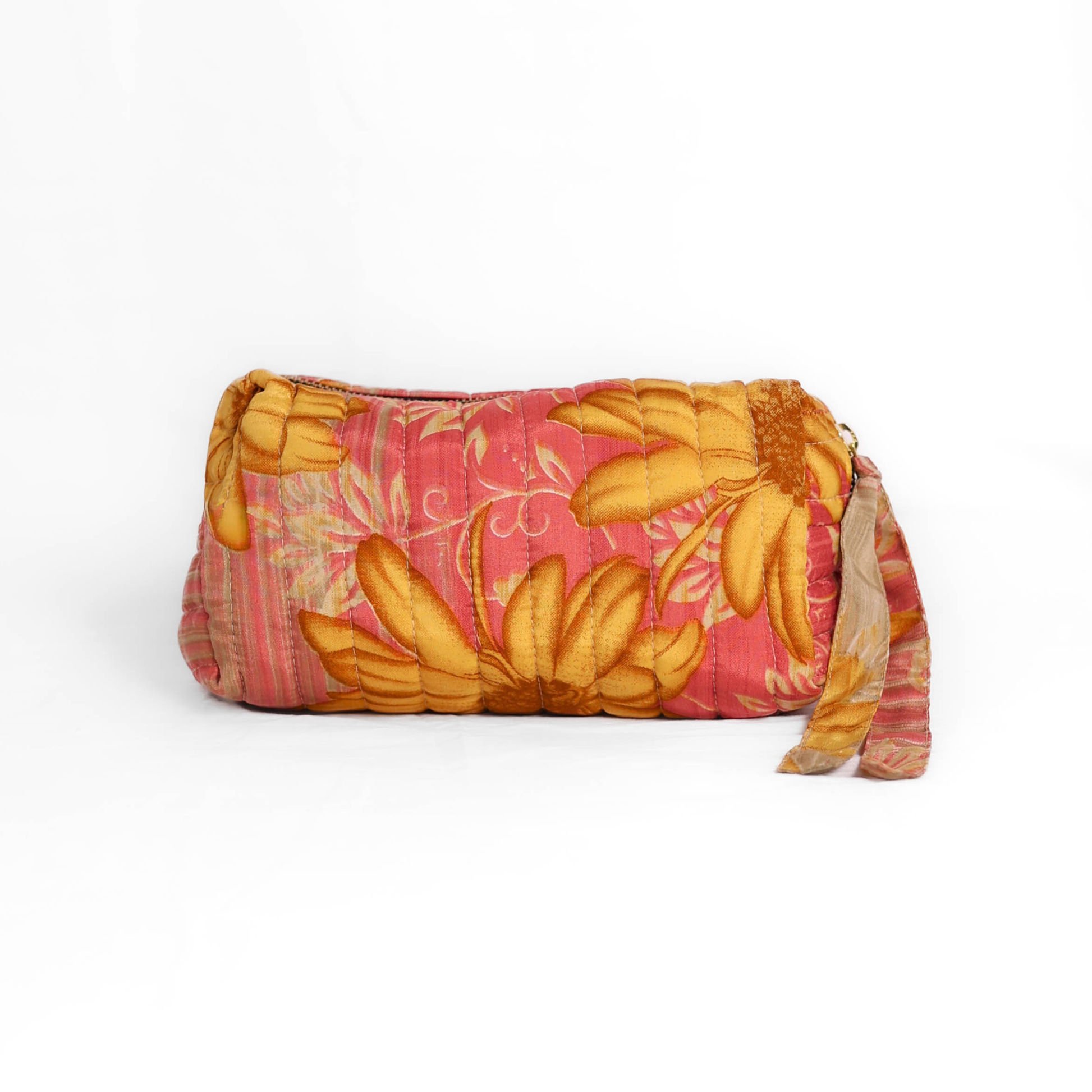 Quilted dumpling bag made from repurposed vintage sari fabric with stitched detailing and a structured rectangular shape. The bag features a zip closure and a fabric tie