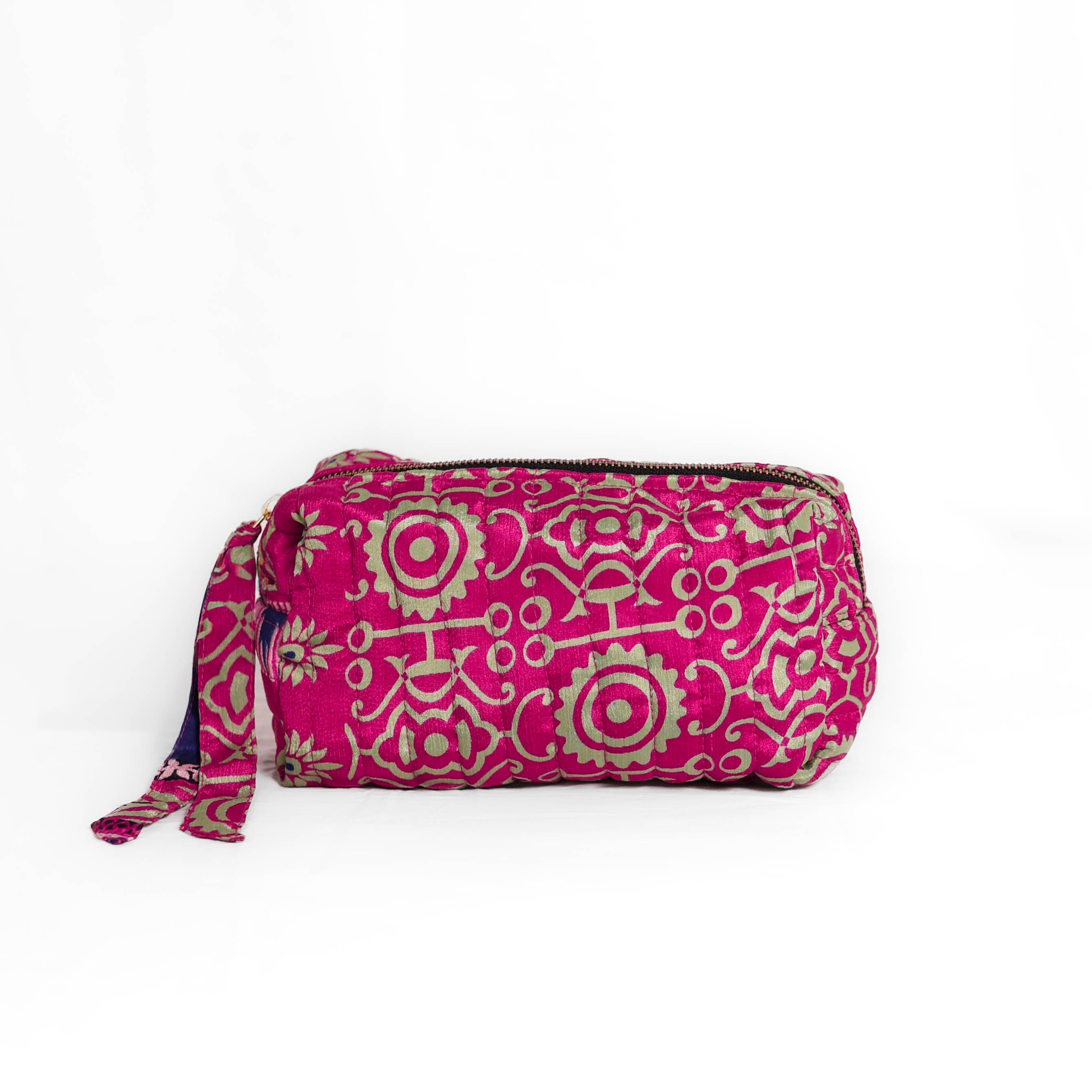Quilted dumpling bag made from repurposed vintage sari fabric with stitched detailing and a structured rectangular shape. The bag features a zip closure and a fabric tie
