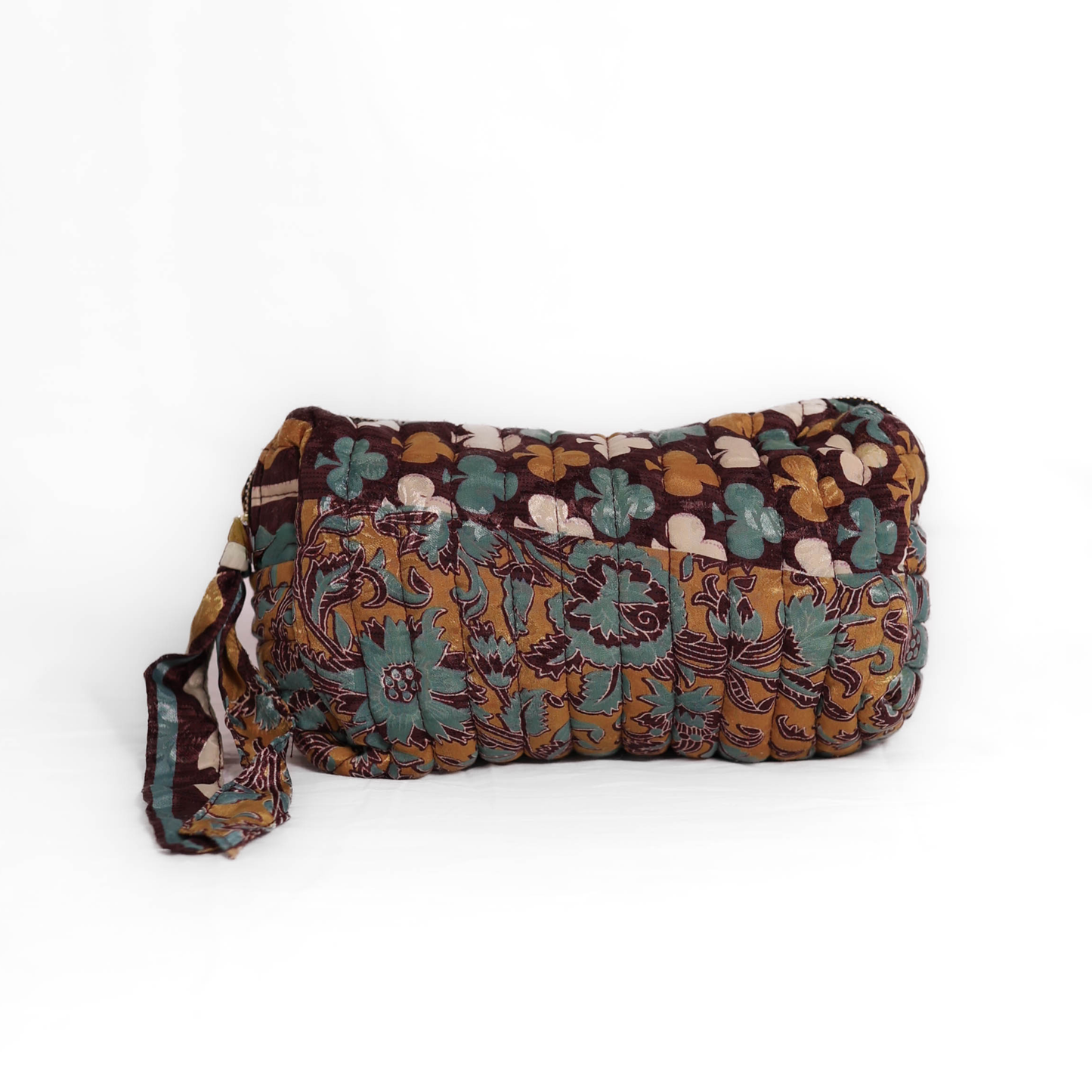 Quilted dumpling bag made from repurposed vintage sari fabric with stitched detailing and a structured rectangular shape. The bag features a zip closure and a fabric tie
