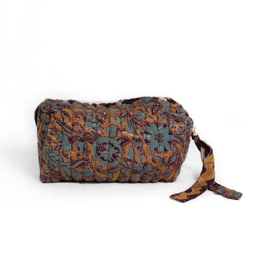 Quilted dumpling bag made from repurposed vintage sari fabric with stitched detailing and a structured rectangular shape. The bag features a zip closure and a fabric tie
