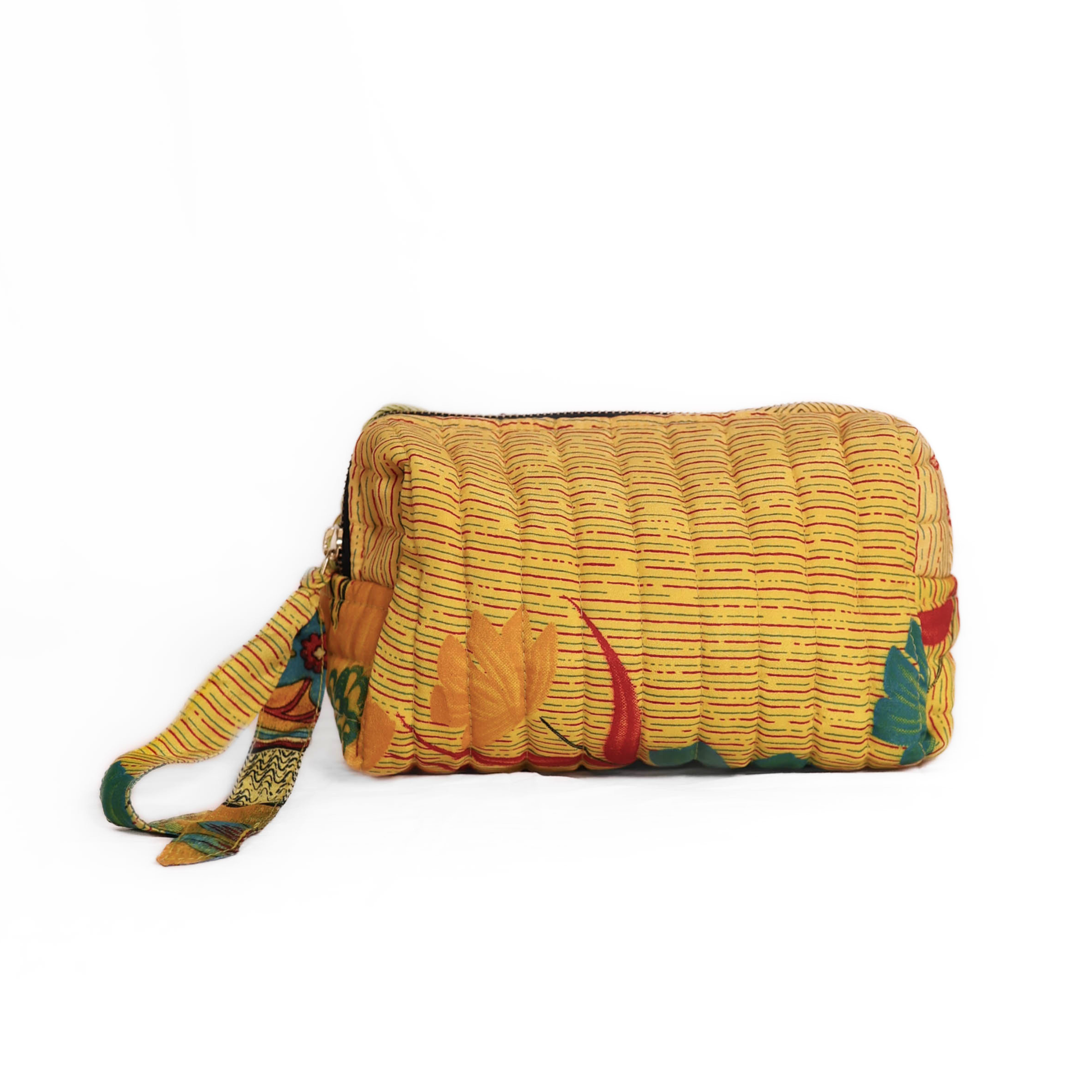 Quilted dumpling bag made from repurposed vintage sari fabric with stitched detailing and a structured rectangular shape. The bag features a zip closure and a fabric tie
