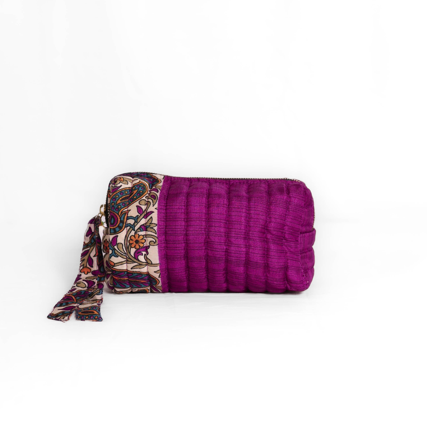 Quilted dumpling bag made from repurposed vintage sari fabric with stitched detailing and a structured rectangular shape. The bag features a zip closure and a fabric tie
