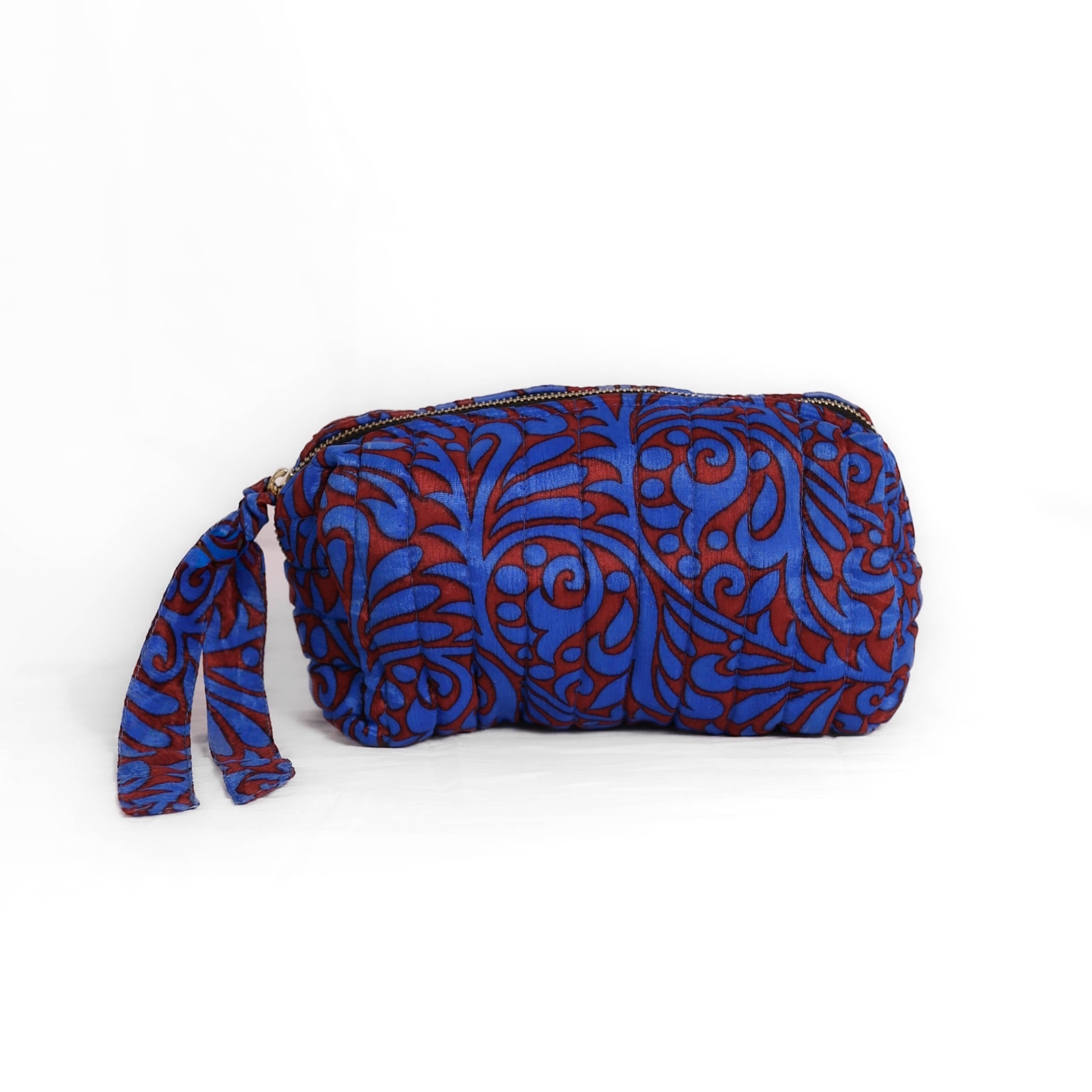 Quilted dumpling bag made from repurposed vintage sari fabric with stitched detailing and a structured rectangular shape. The bag features a zip closure and a fabric tie
