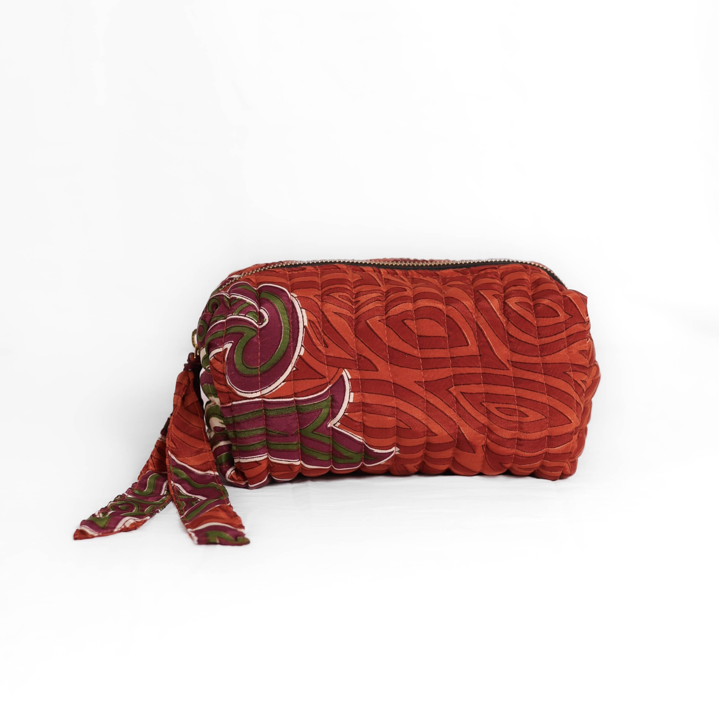 Quilted dumpling bag made from repurposed vintage sari fabric with stitched detailing and a structured rectangular shape. The bag features a zip closure and a fabric tie