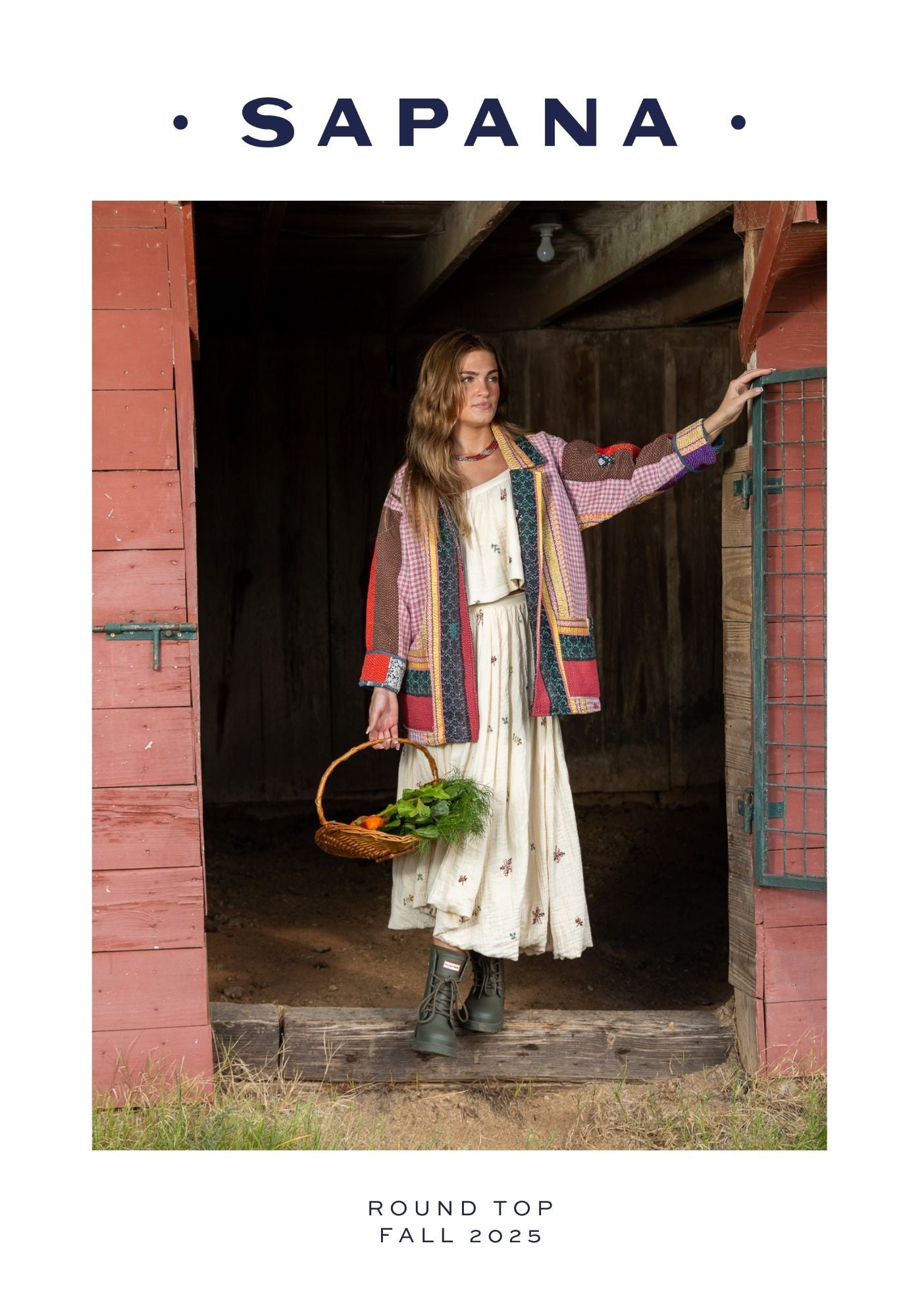 She wears a layered, bohemian outfit: a patterned, multicolor jacket with contrasting panels and textures over a soft, cream dress with delicate detailing. The look is styled with practical yet stylish boots and a woven basket filled with fresh vegetables, adding a harvest, artisanal feel.