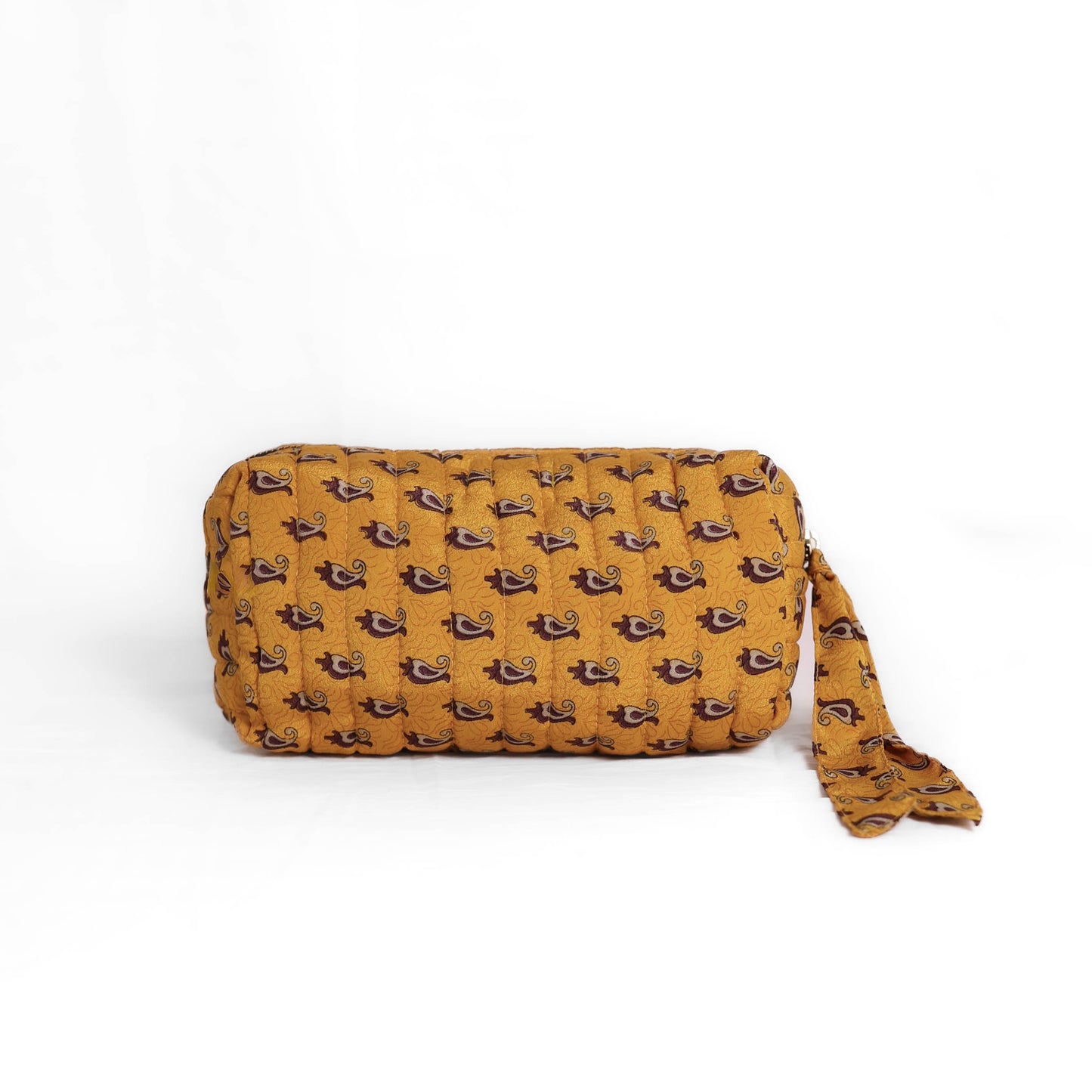 Quilted dumpling bag made from repurposed vintage sari fabric with stitched detailing and a structured rectangular shape. The bag features a zip closure and a fabric tie
