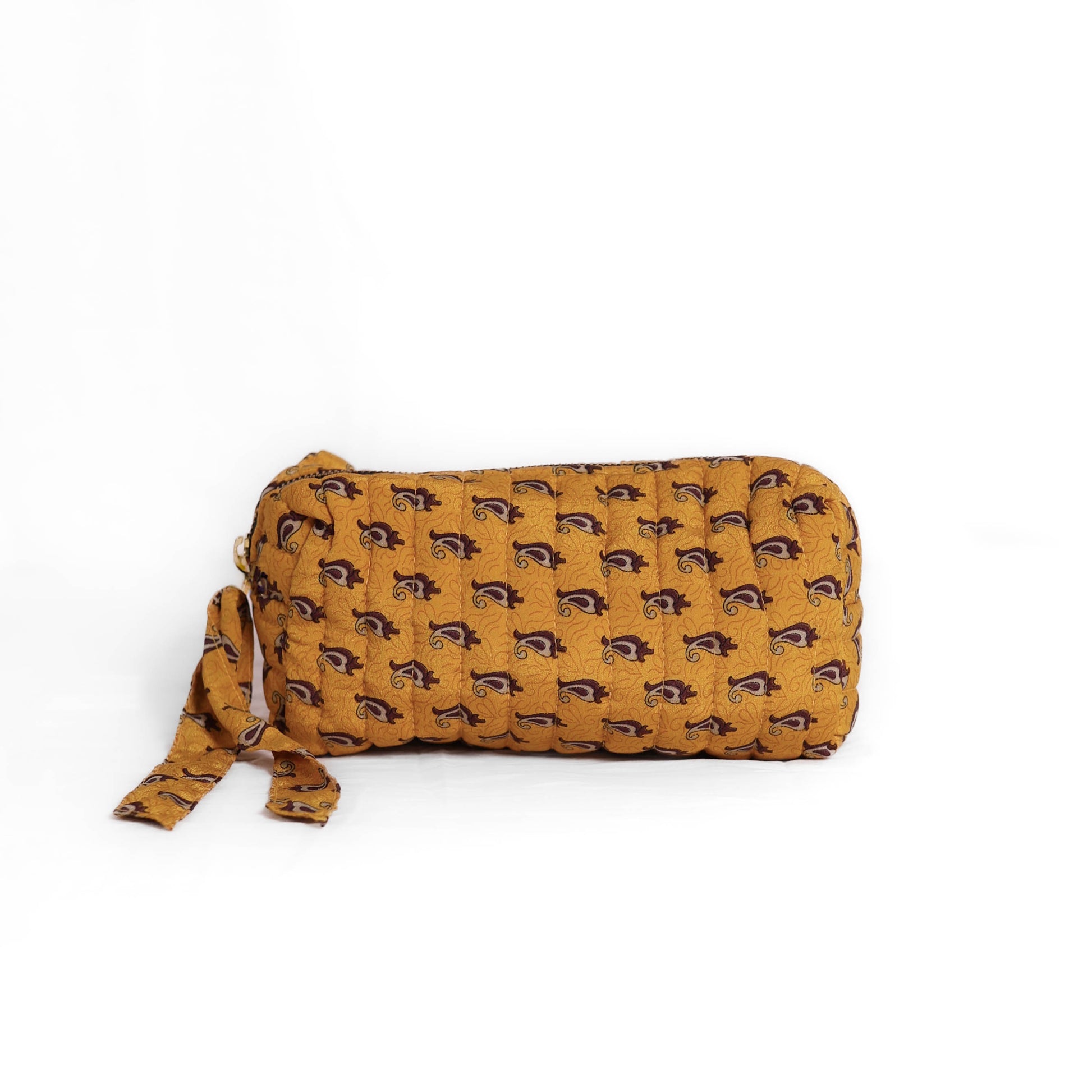 Quilted dumpling bag made from repurposed vintage sari fabric with stitched detailing and a structured rectangular shape. The bag features a zip closure and a fabric tie
