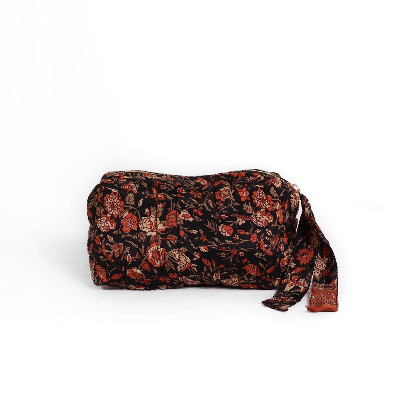 Quilted dumpling bag made from repurposed vintage sari fabric with stitched detailing and a structured rectangular shape. The bag features a zip closure and a fabric tie

