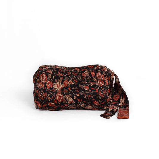 Quilted dumpling bag made from repurposed vintage sari fabric with stitched detailing and a structured rectangular shape. The bag features a zip closure and a fabric tie
