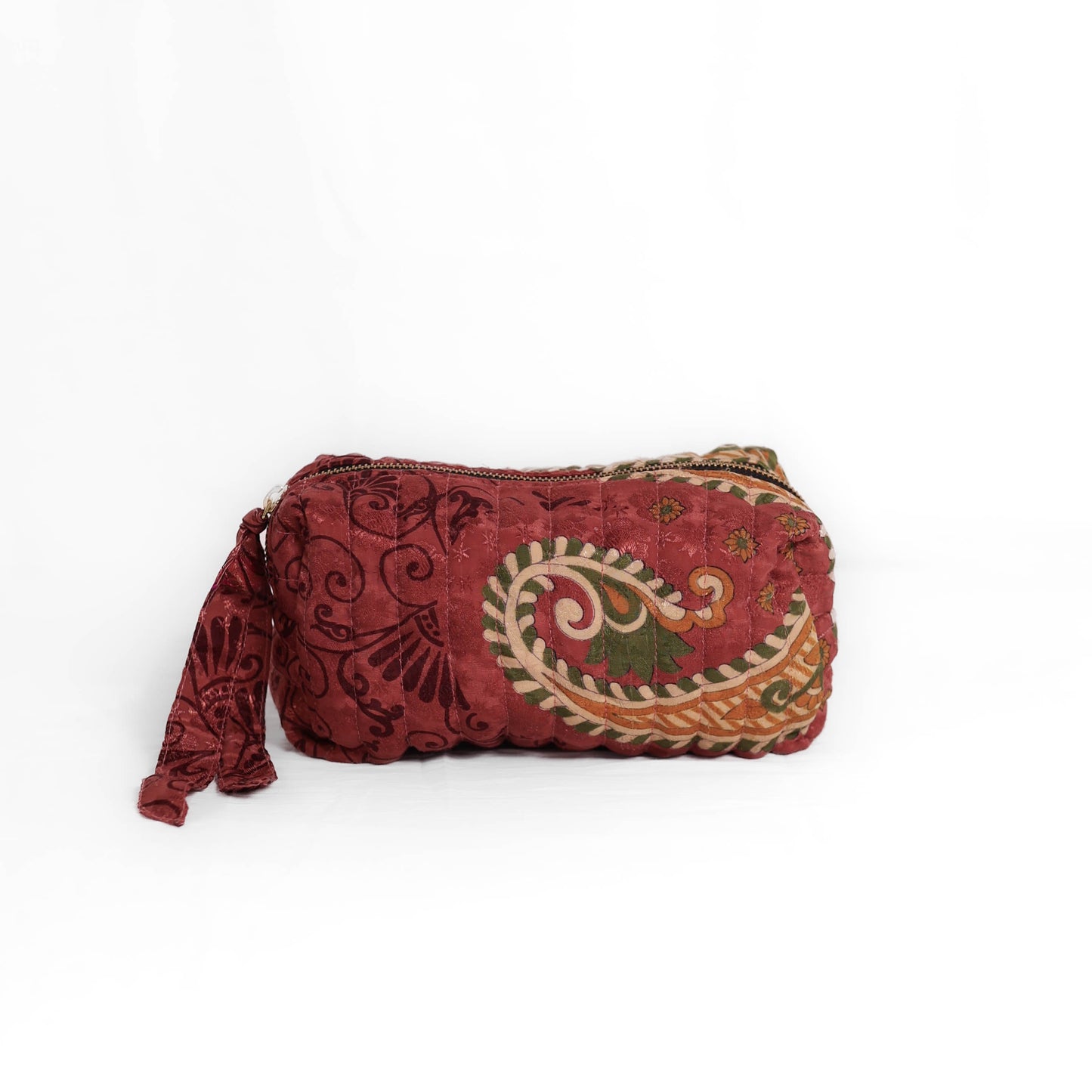 Quilted dumpling bag made from repurposed vintage sari fabric with stitched detailing and a structured rectangular shape. The bag features a zip closure and a fabric tie
