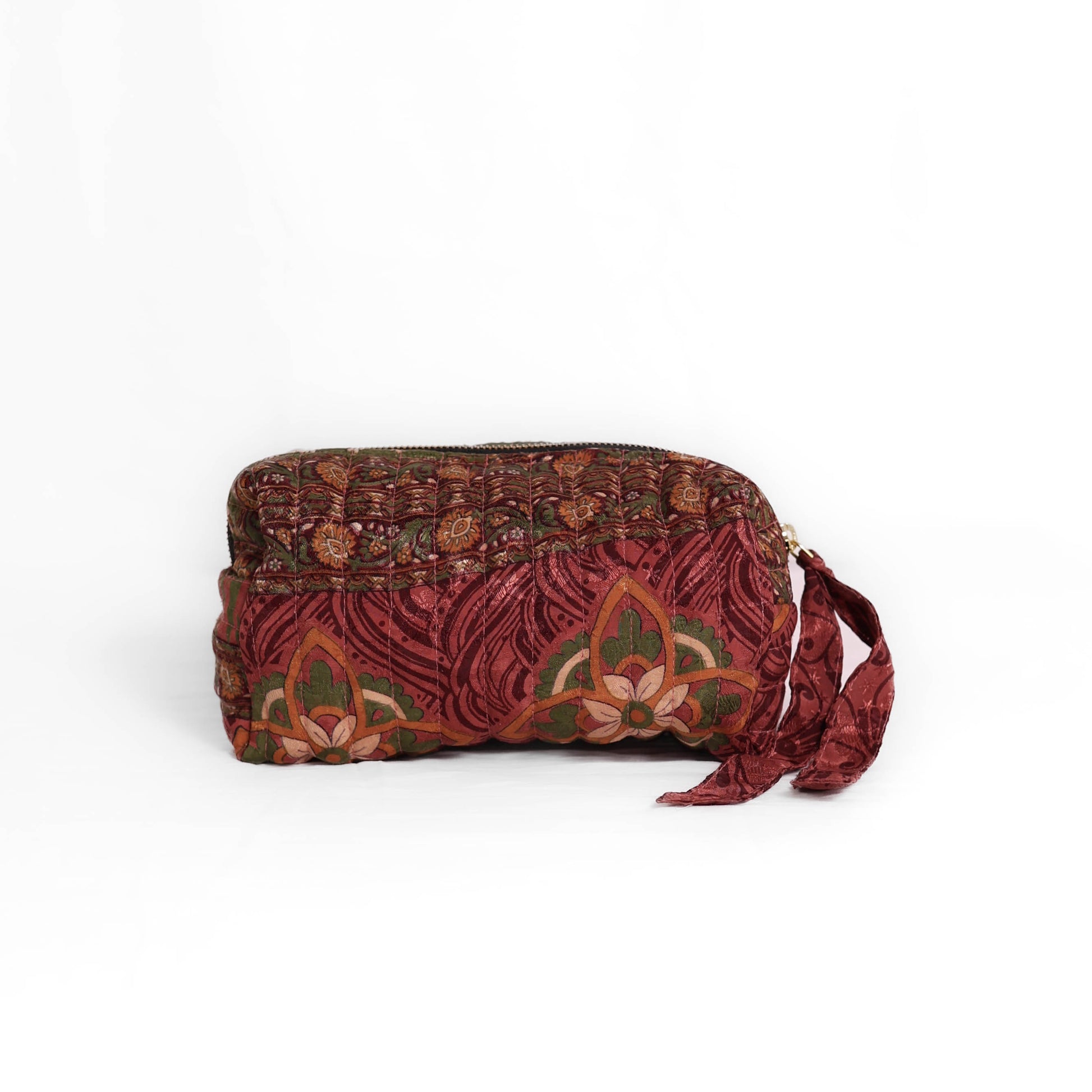 Quilted dumpling bag made from repurposed vintage sari fabric with stitched detailing and a structured rectangular shape. The bag features a zip closure and a fabric tie
